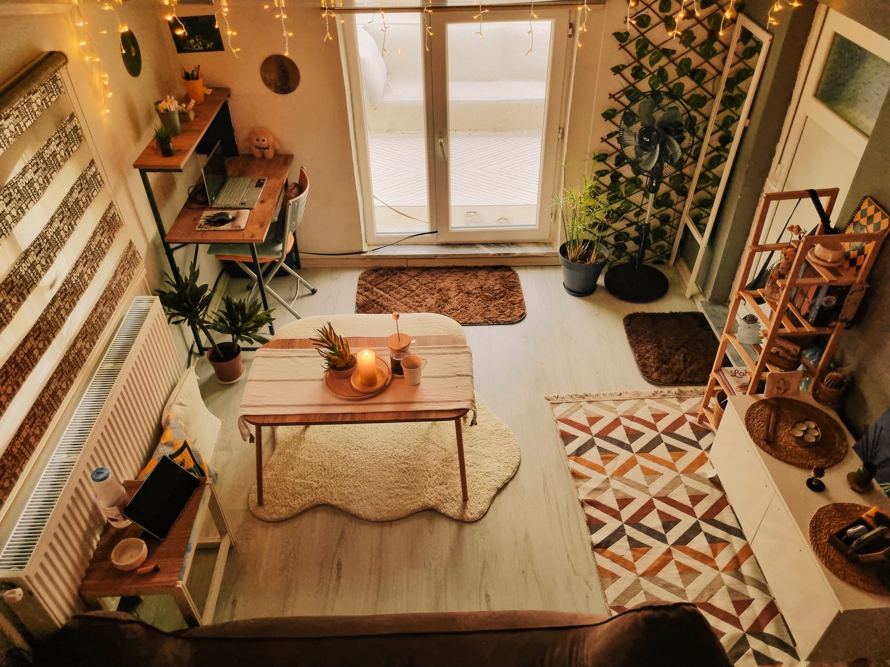 A cozy, warmly lit living room with a wooden desk, plants, and lighting, set up for at-home writing work.